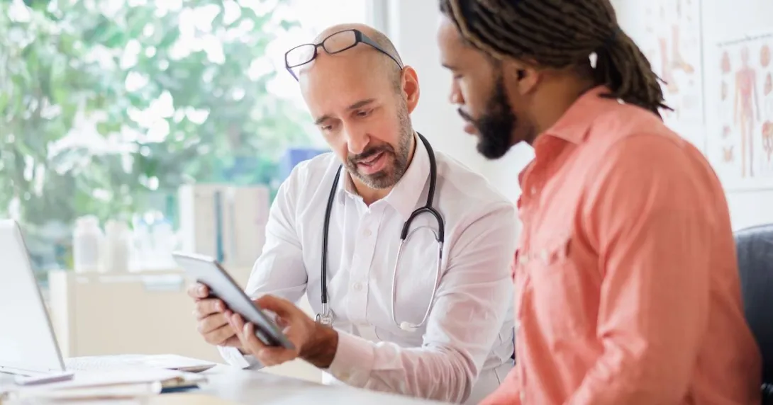 Healthcare provider sitting with a patient and showing them a tablet Healthcare provider sitting with a patient and showing them a tablet
