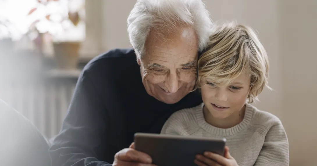 Older man looking at a tablet computer with a young boy Older man looking at a tablet computer with a young boy