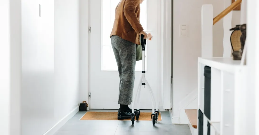 A senior adult using a walker opening a door A senior adult using a walker opening a door