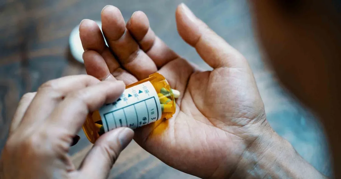 Person holding a pill bottle and pouring medication into their hand Person holding a pill bottle and pouring medication into their hand