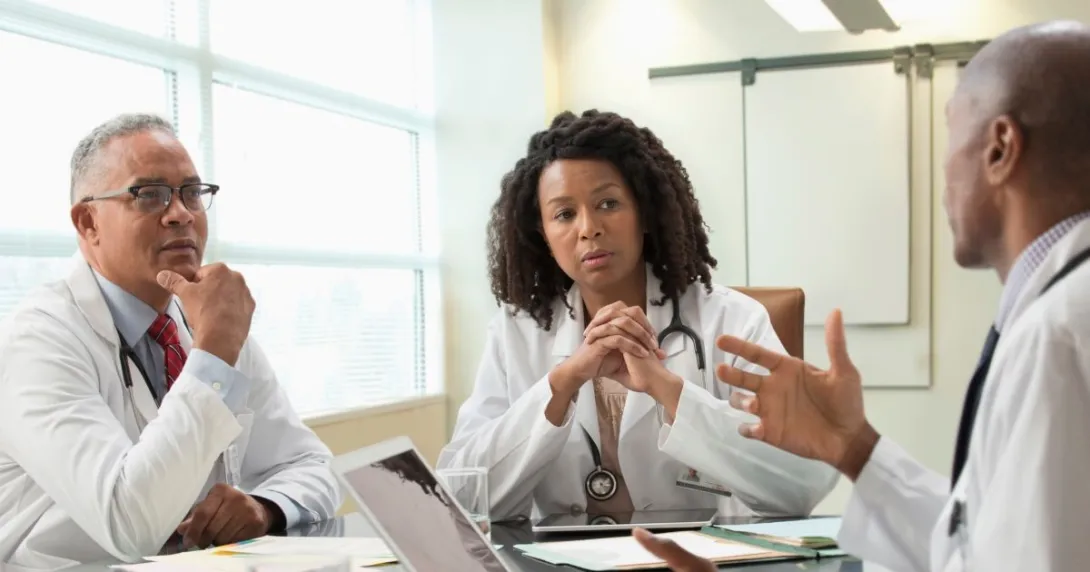 Three people sit around a table Three people sit around a table