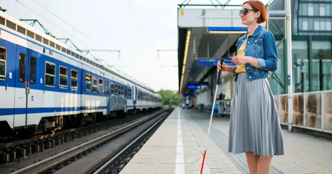Blind person standing on a train station platform Blind person standing on a train station platform