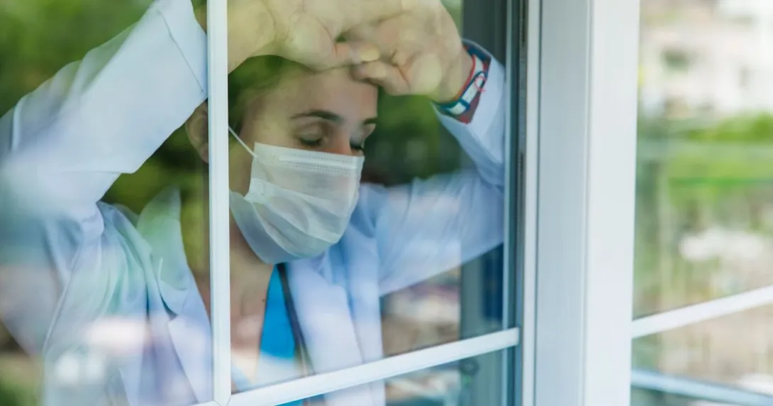 Medical worker leans against window