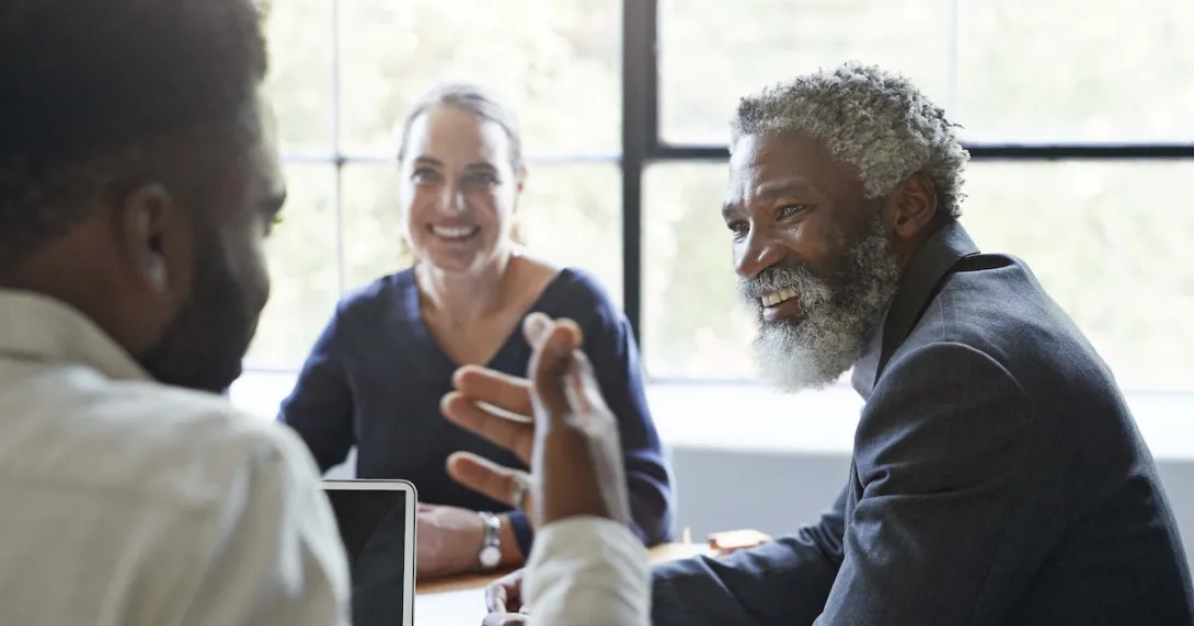 Three business people sitting around a table and talking Three business people sitting around a table and talking