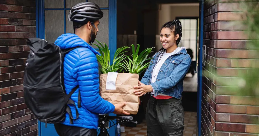 Food delivery person handing a bag to a person standing in their doorway Food delivery person handing a bag to a person standing in their doorway