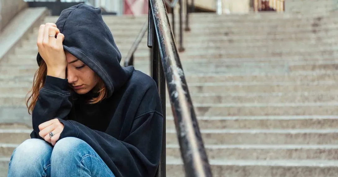 Person sitting on steps with their head in their hands Person sitting on steps with their head in their hands
