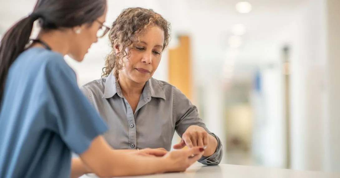 Healthcare provider standing up and talking to a patient who is also standing Healthcare provider standing up and talking to a patient who is also standing