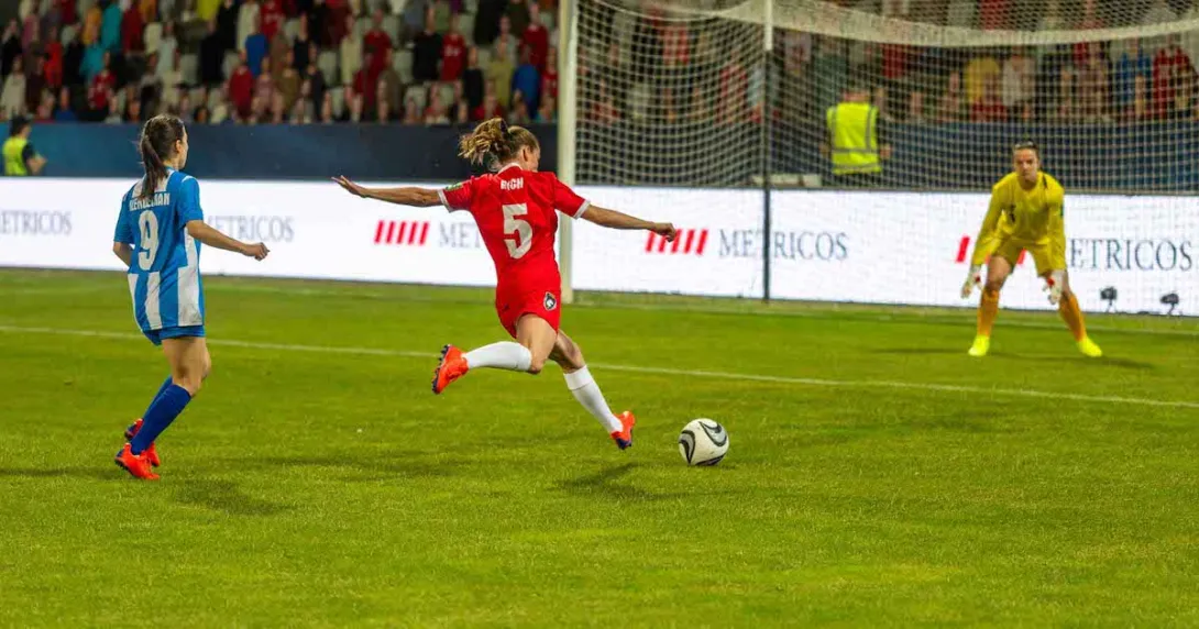 Soccer players on a field with one kicking a ball into the goal Soccer players on a field with one kicking a ball into the goal