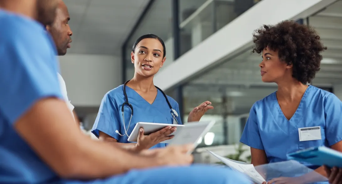 Three healthcare providers sitting in a circle and talking to each other Three healthcare providers sitting in a circle and talking to each other