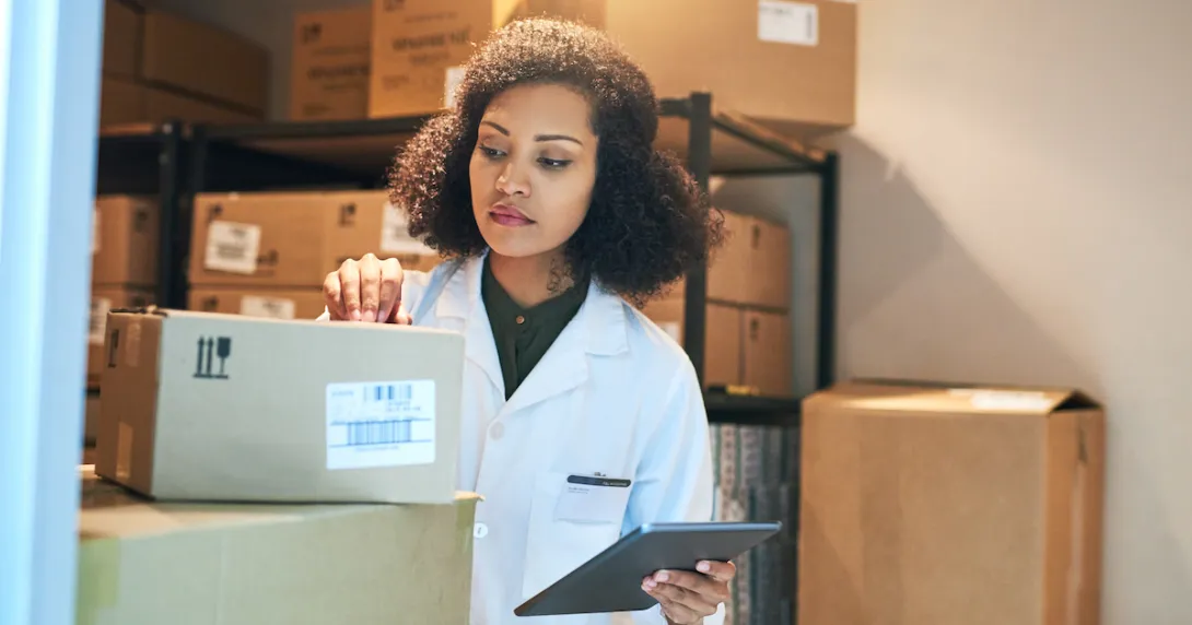 A person using a digital tablet while doing inventory in the storeroom of a pharmacy A person using a digital tablet while doing inventory in the storeroom of a pharmacy