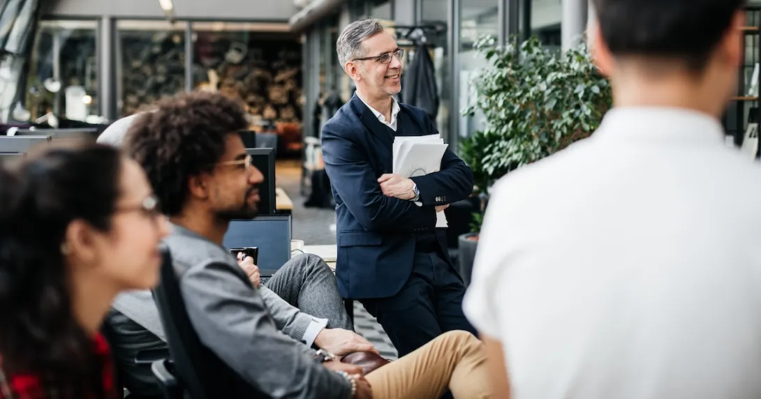 Numerous individuals sitting in a half circle looking at something off-screen Numerous individuals sitting in a half circle looking at something off-screen