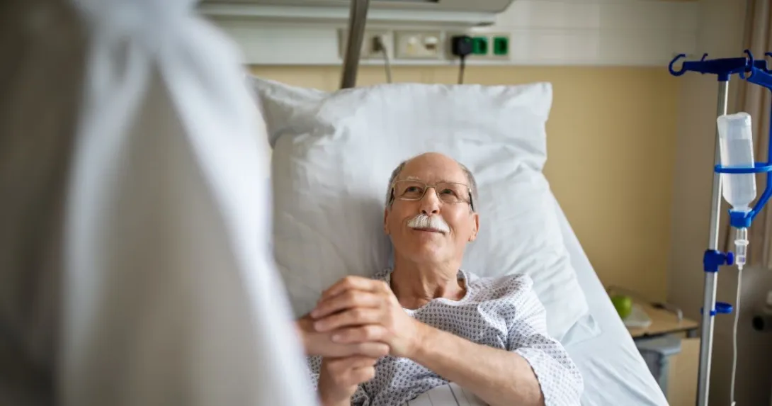 person in hospital bed holds hand of person in white lab coat person in hospital bed holds hand of person in white lab coat