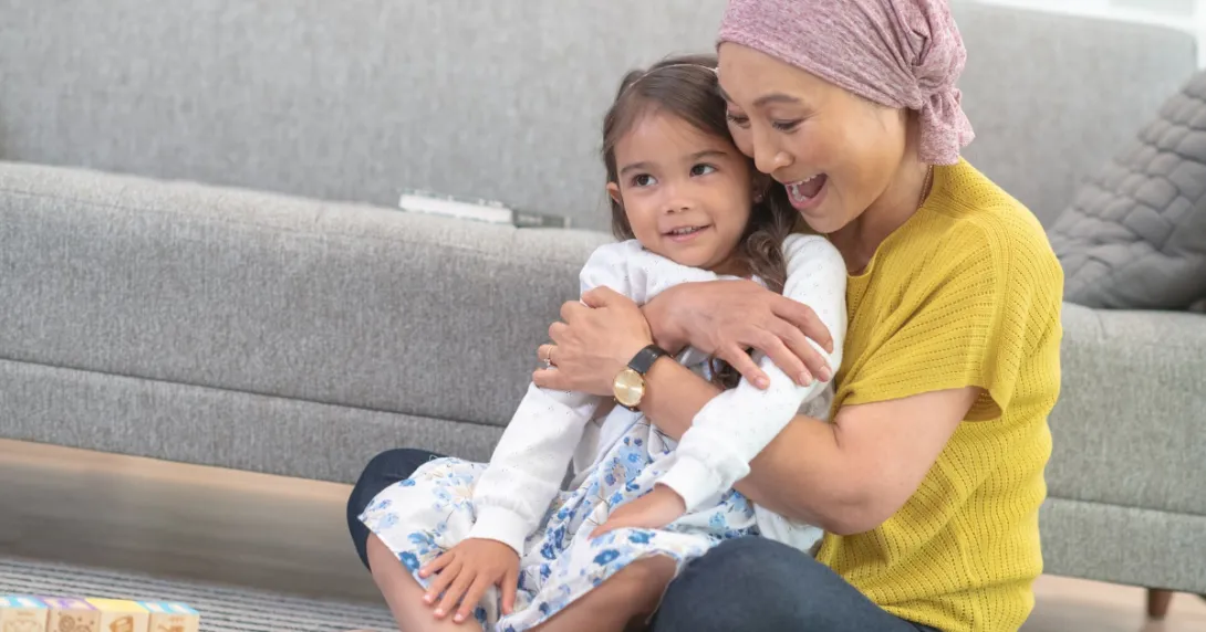 Person and child embracing while sitting on the floor Person and child embracing while sitting on the floor