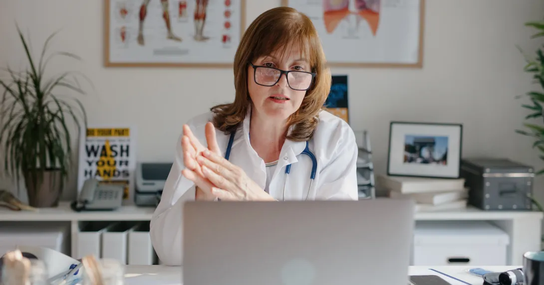 Healthcare professional sitting at a desk looking at a computer Healthcare professional sitting at a desk looking at a computer