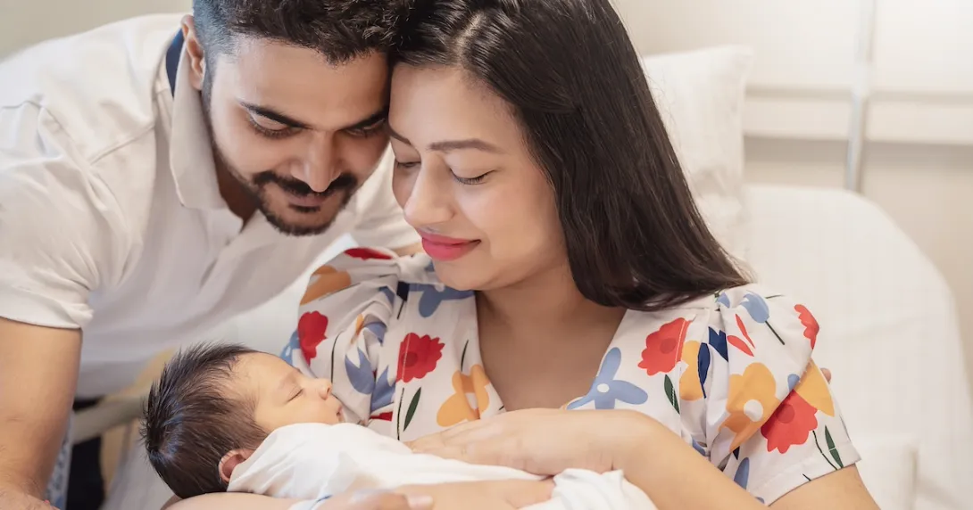 Two people sitting in a bed holding another person Two people sitting in a bed holding another person