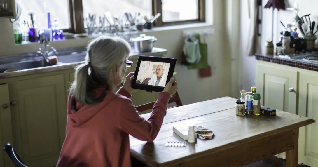 Person sitting at a table looking at a tablet Person sitting at a table looking at a tablet