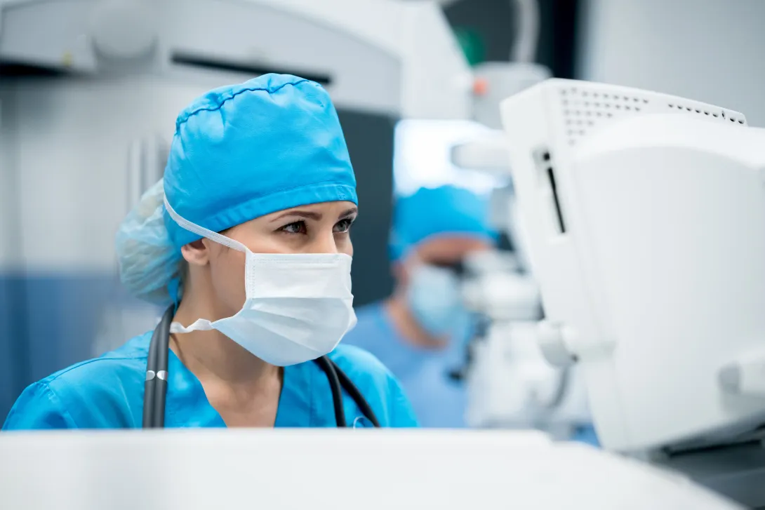 Surgeon standing in front of a computer dressed in surgical gear Surgeon standing in front of a computer dressed in surgical gear