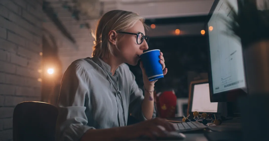 Person sitting at their computer drinking something out of a coffee cup Person sitting at their computer drinking something out of a coffee cup