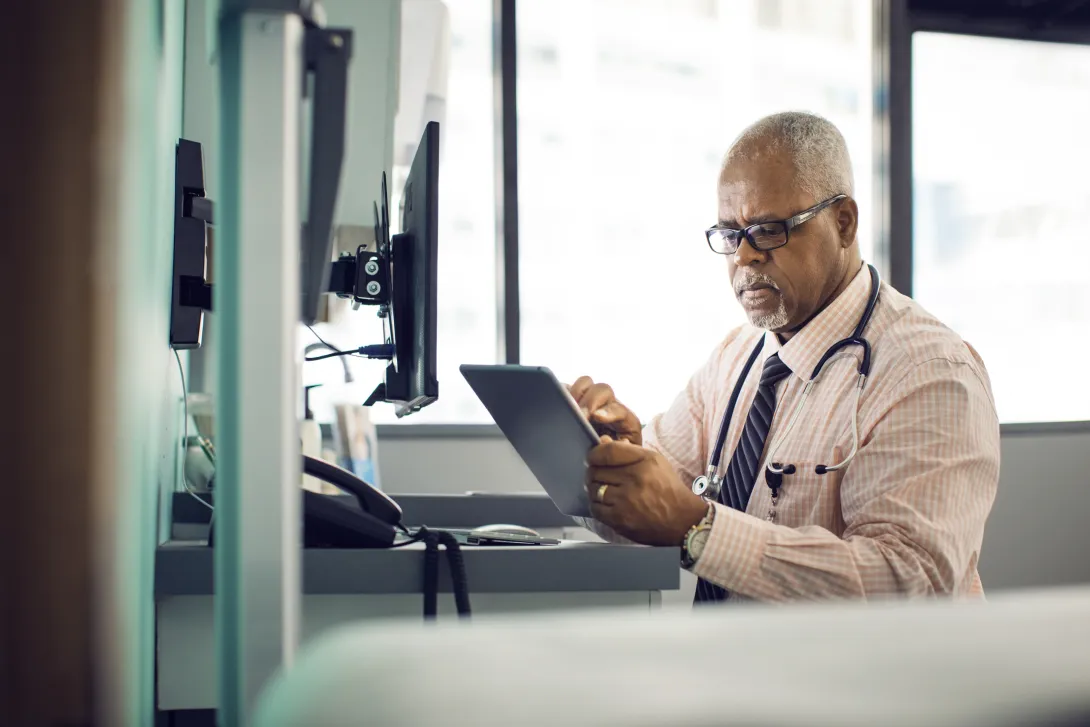 Healthcare provider sitting at a desk while looking at a tablet