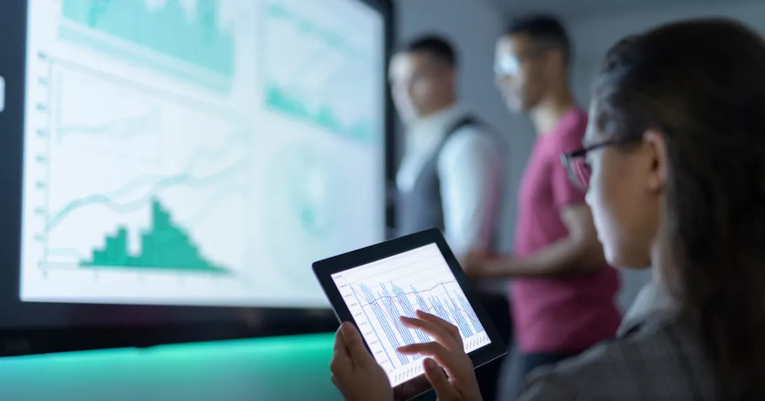 Three people in a room looking at different graphs on separate screens Three people in a room looking at different graphs on separate screens