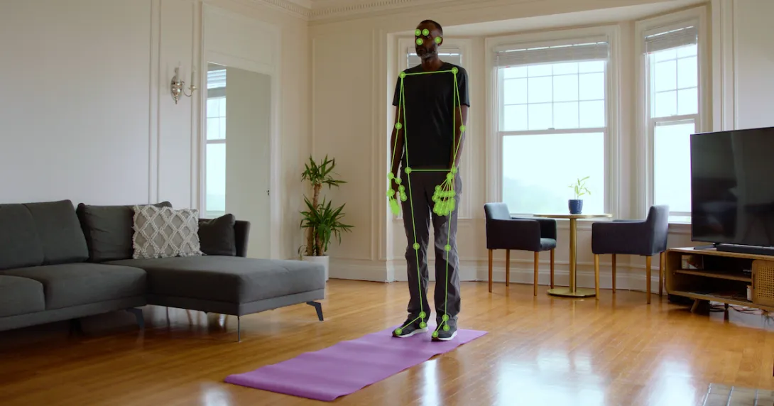 A man standing on a yoga mat while computer vision monitors his movement