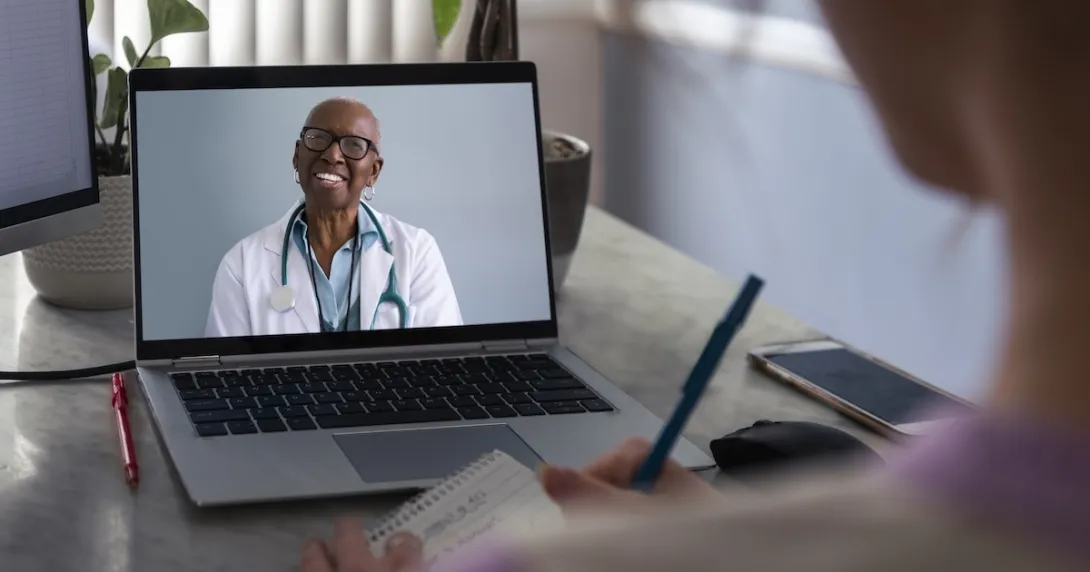 Physician interacting remotely with a person via laptop Physician interacting remotely with a person via laptop