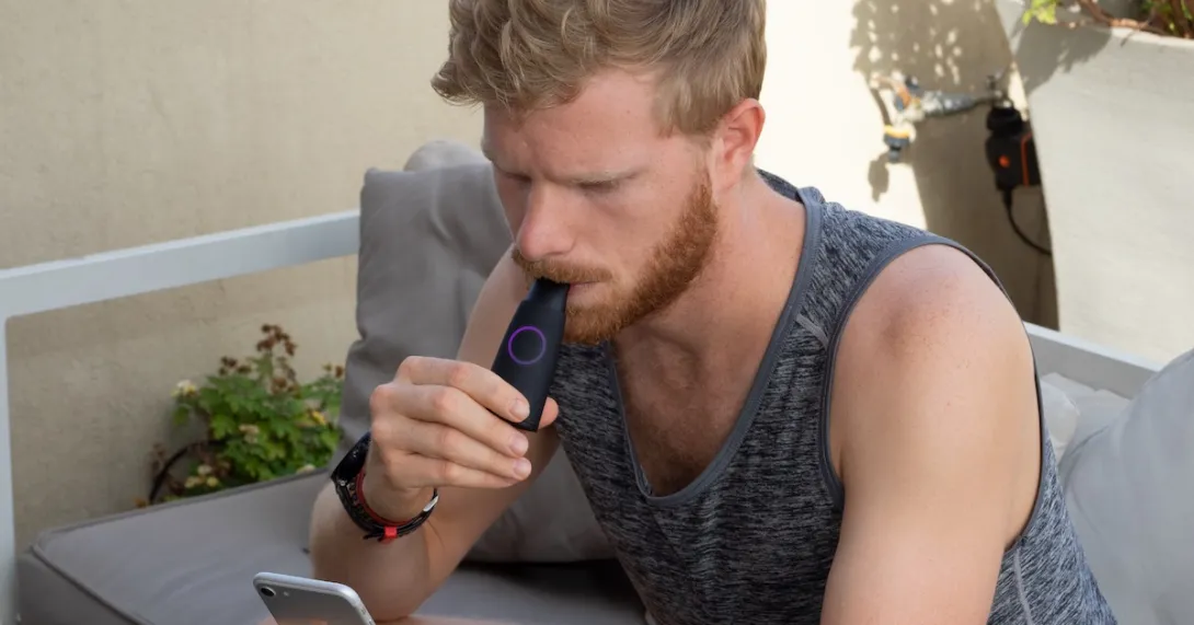 A man using the Lumen device while looking at his phone. A man using the Lumen device while looking at his phone.