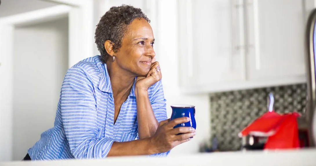 Person leaning against a counter holding a coffee cup Person leaning against a counter holding a coffee cup