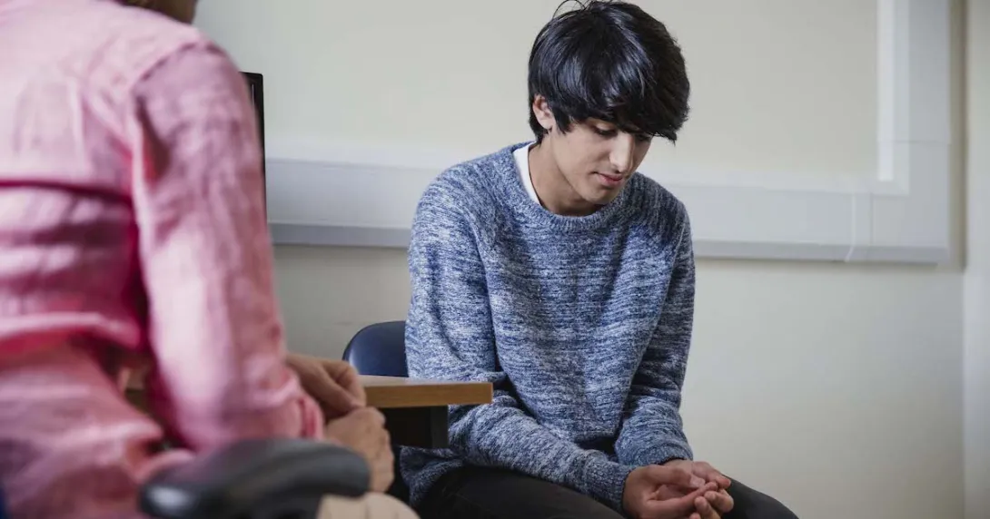 Two people sitting in a room, one with their head down Two people sitting in a room, one with their head down