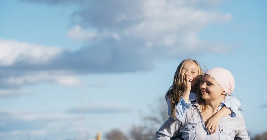 Person wearing a scarf on their head holding a child on their back with the sky behind them Person wearing a scarf on their head holding a child on their back with the sky behind them
