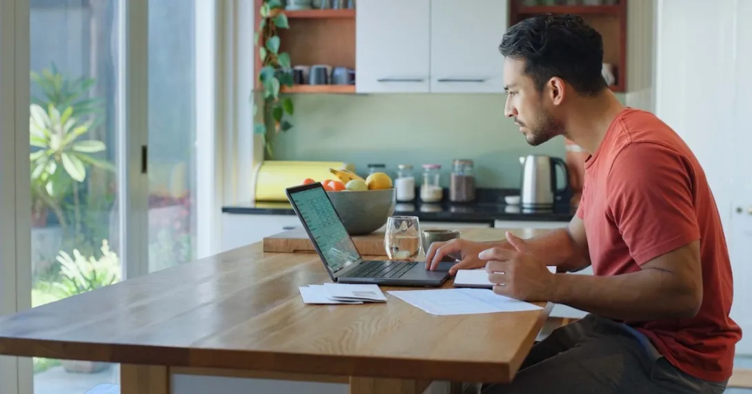 Person sitting at a table while looking at a computer Person sitting at a table while looking at a computer