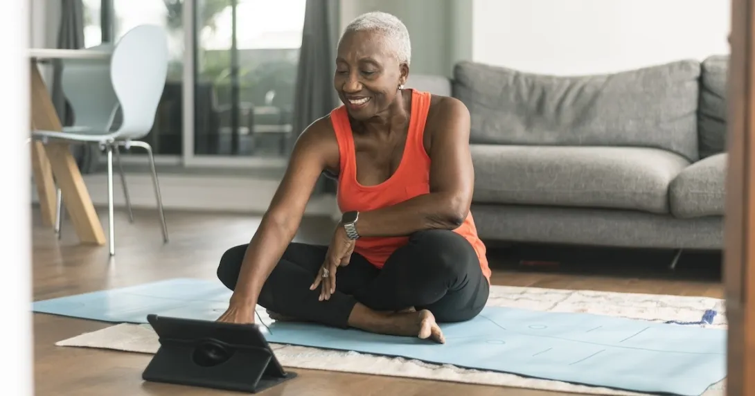 Person sitting on exercise mat interacting using a tablet Person sitting on exercise mat interacting using a tablet