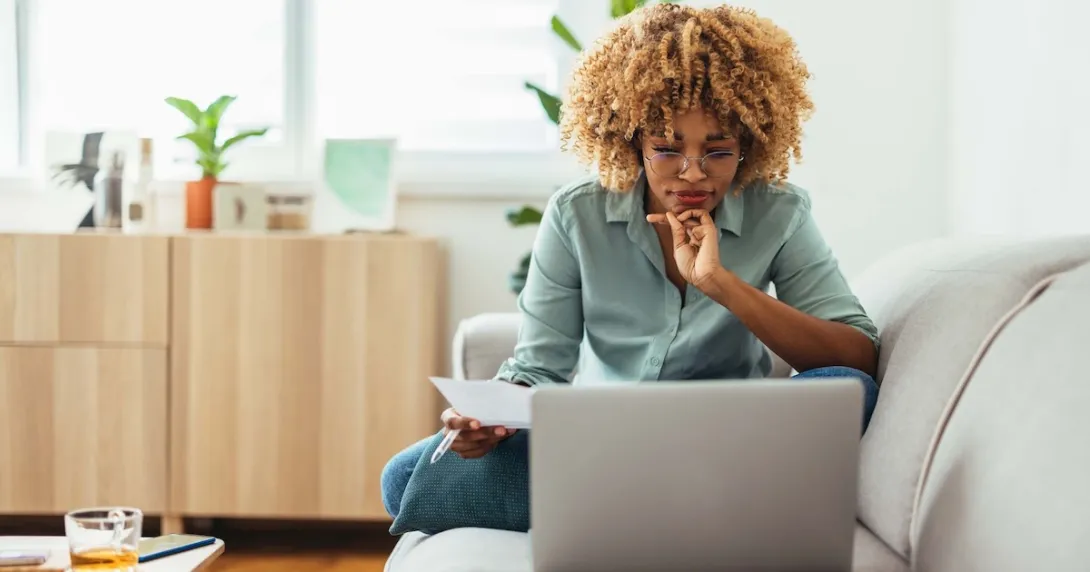 Person sitting on their couch while looking at a computer Person sitting on their couch while looking at a computer