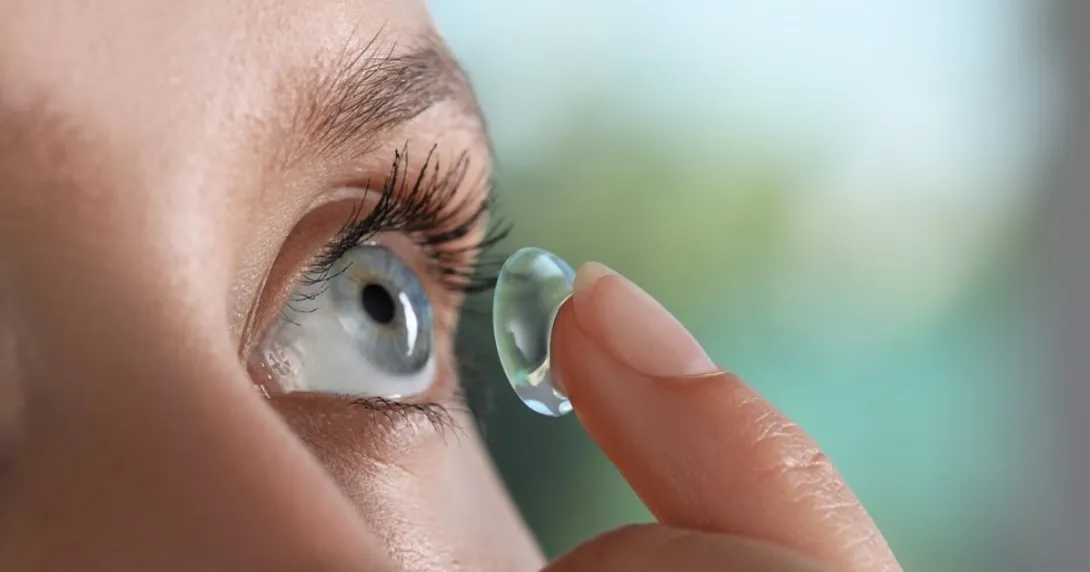 Person inserting a contact lens into their eye Person inserting a contact lens into their eye
