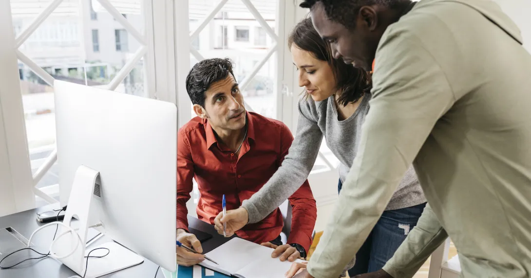 People in an office at a desk talking People in an office at a desk talking