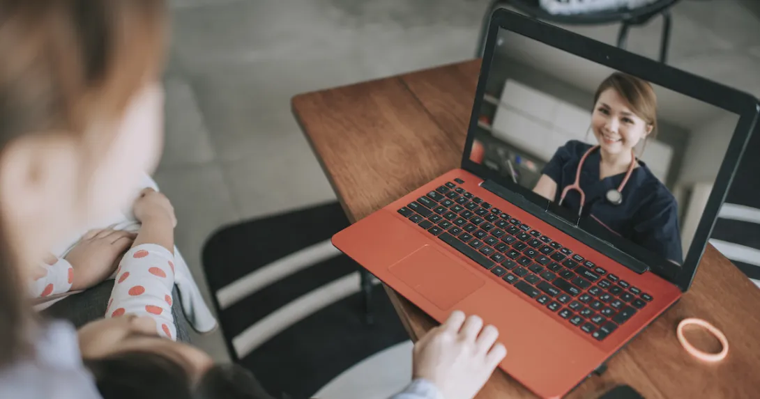 Person sitting down with a computer in front of them with a healthcare provider on the screen Person sitting down with a computer in front of them with a healthcare provider on the screen