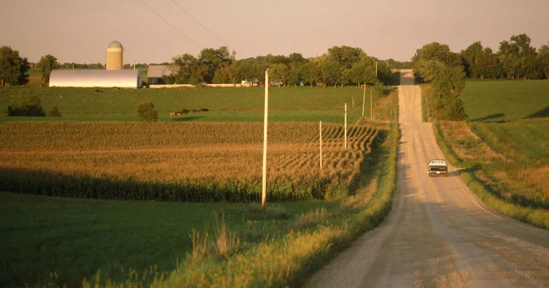 A truck driving on a gravel road near a farm A truck driving on a gravel road near a farm
