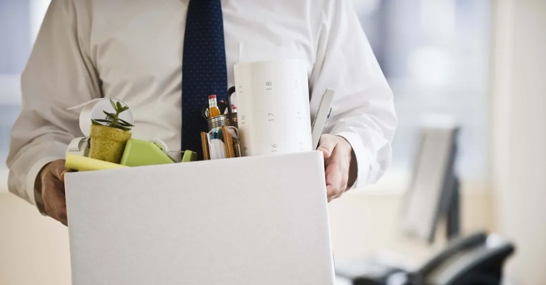A man leaving an office carrying a box of his belongings.