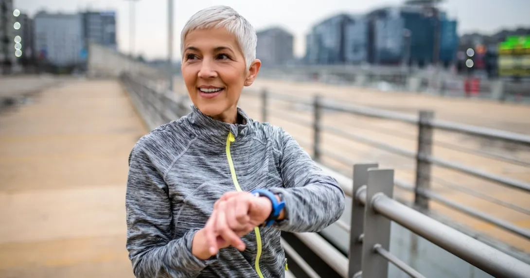 Person looking at smartwatch while standing outdoors Person looking at smartwatch while standing outdoors