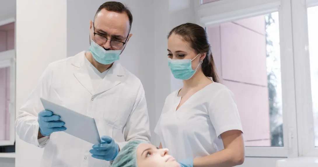 Dentist and his assistant using tablet in the process of treating teeth of patient Dentist and his assistant using tablet in the process of treating teeth of patient