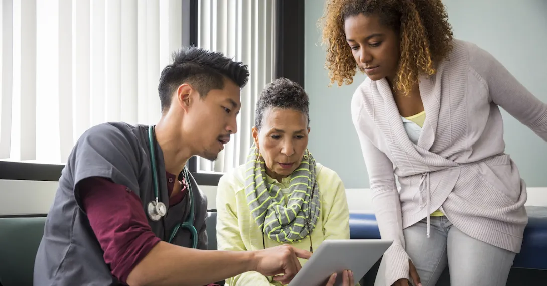 A provider showing a patient and their family member information on a tablet A provider showing a patient and their family member information on a tablet