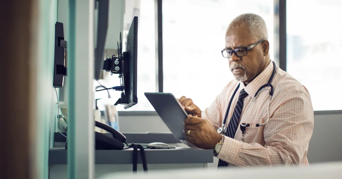 A doctor sitting at his desk using a tablet A doctor sitting at his desk using a tablet