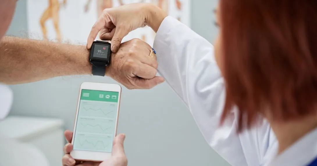 A doctor helping a patient sync heart rate data from a wearable to a smartphone. A doctor helping a patient sync heart rate data from a wearable to a smartphone.