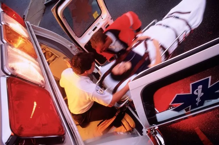 A paramedic pushing a gurney out of an ambulance.