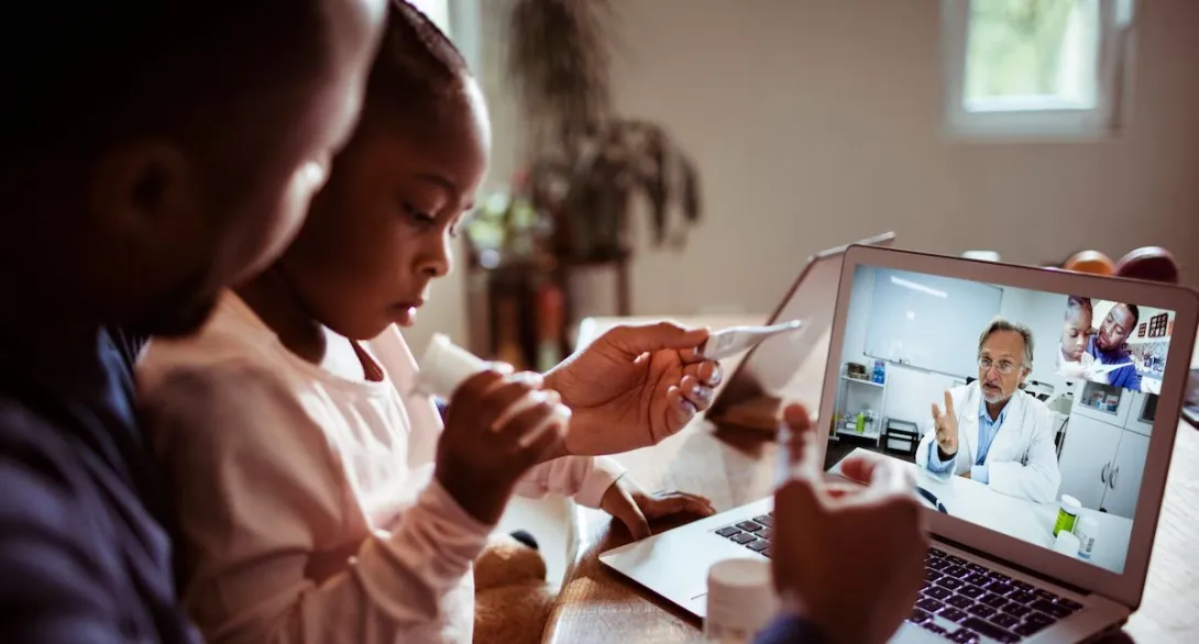 A father and daughter talking to a doctor through a video chat on a laptop. A father and daughter talking to a doctor through a video chat on a laptop.