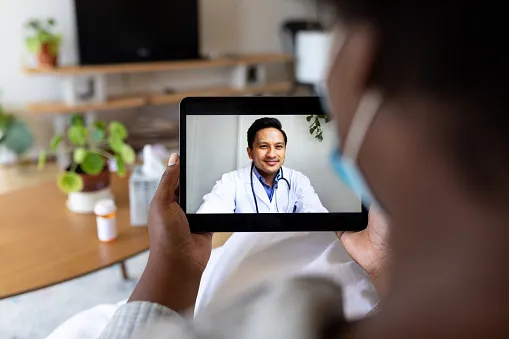 Person holding up a tablet with a telehealth provider on the screen