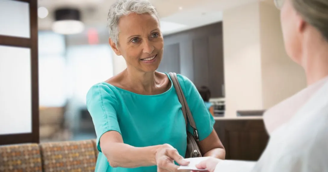 Person handing insurance card to a healthcare worker Person handing insurance card to a healthcare worker