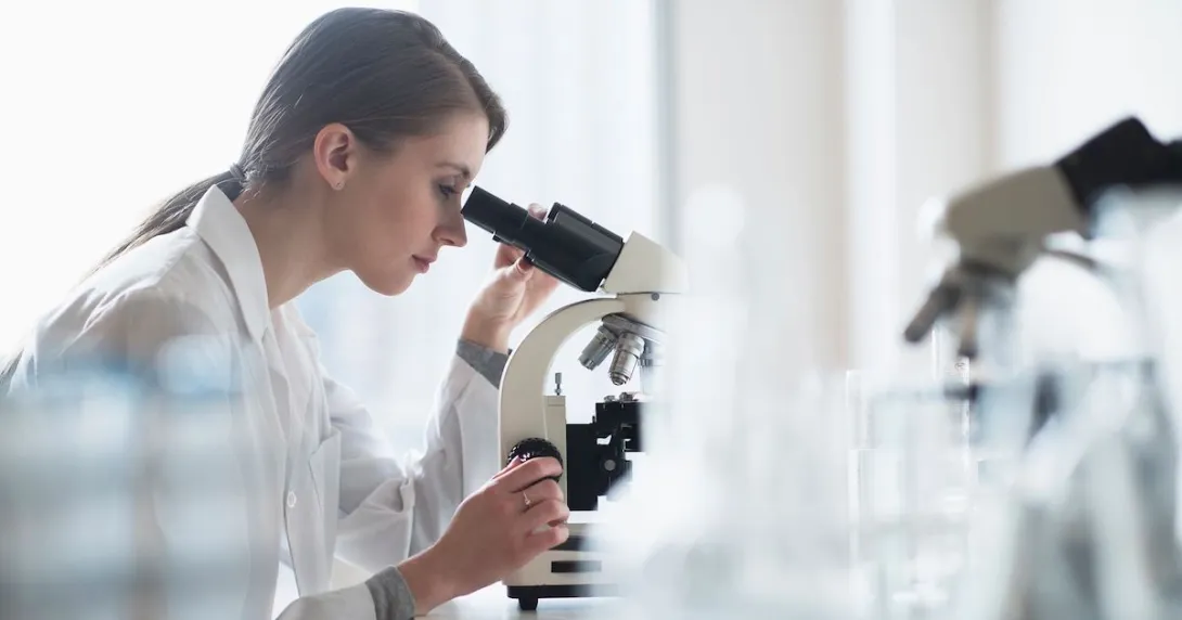 A researcher using a microscope in a lab A researcher using a microscope in a lab