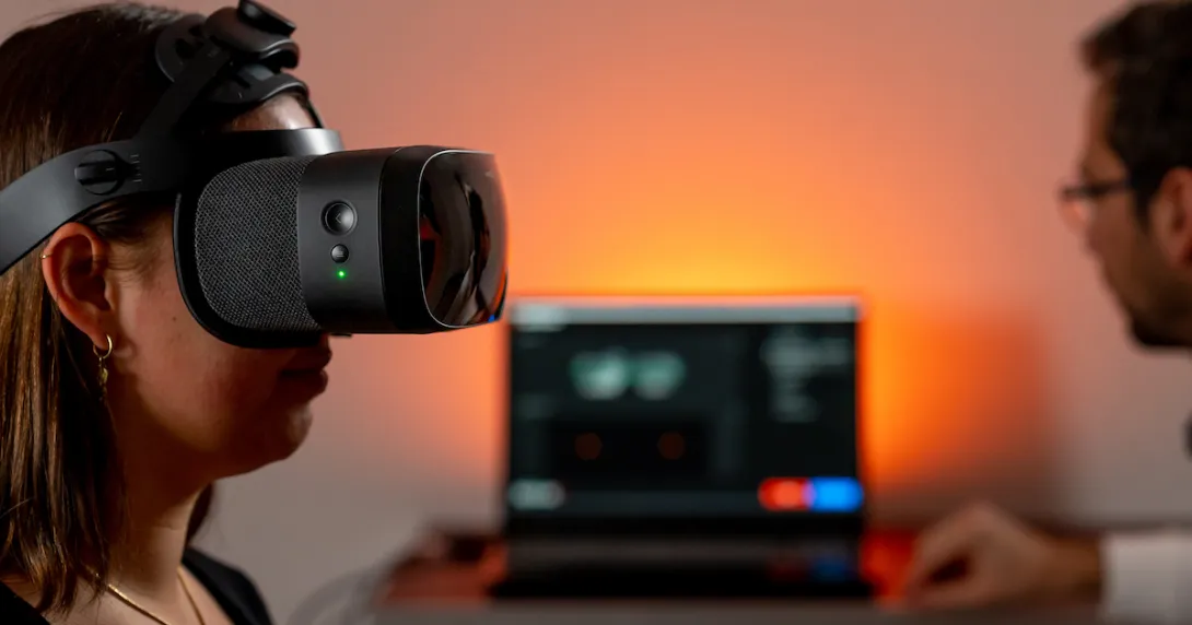 Person wearing a VR headset with a healthcare provider sitting next to them near a computer