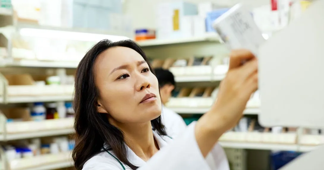 A pharmacist pulling a medication off a shelf A pharmacist pulling a medication off a shelf